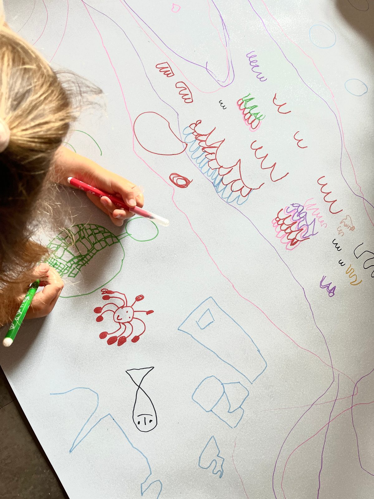 Un enfant dessine et brode sur un grand tissu